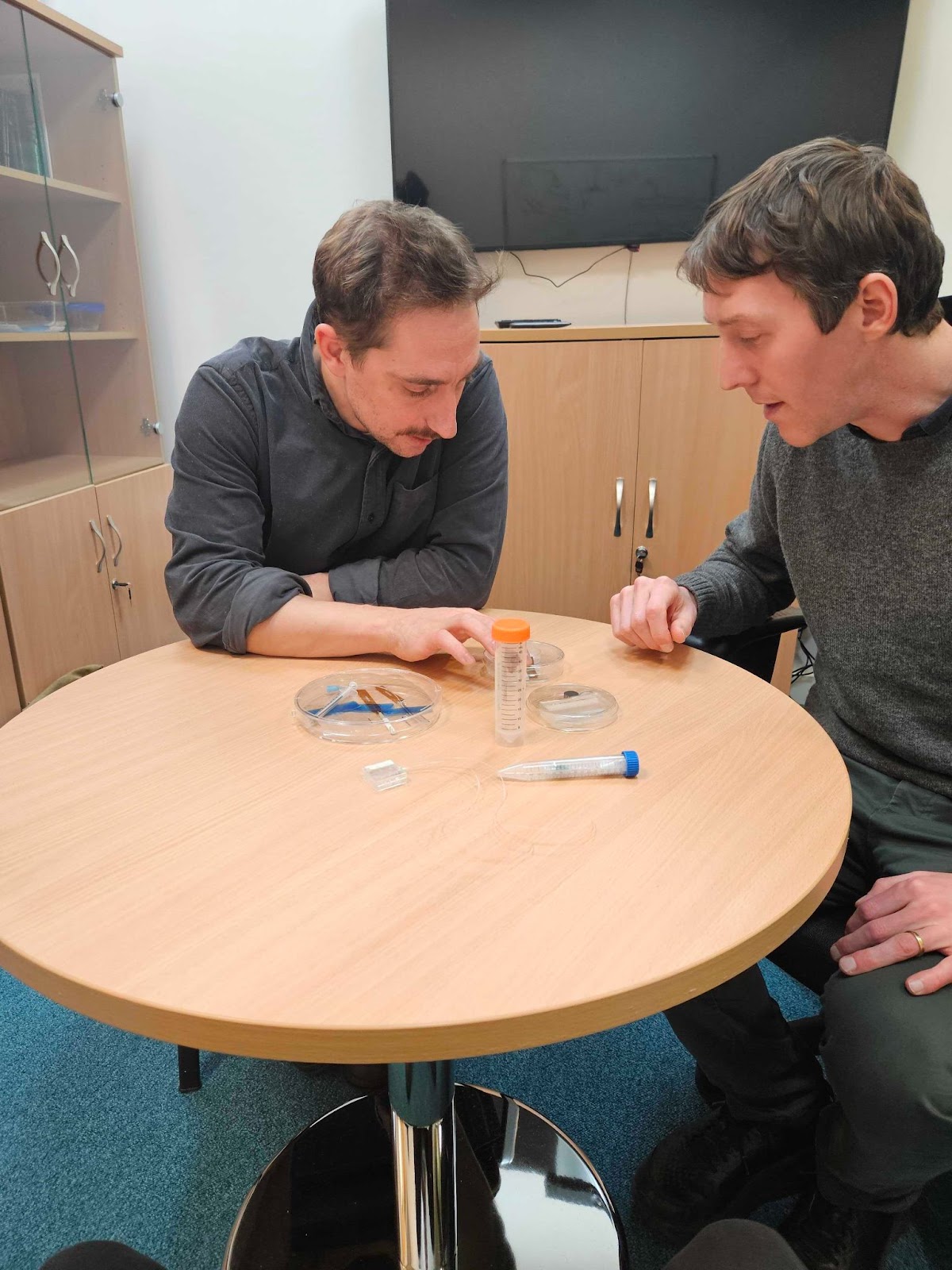 A photo of Jacques and another person looking at items on a table.